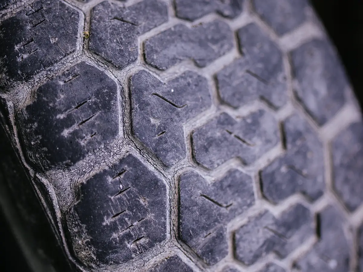 Close view of worn tire tread showing uneven wear on a passenger car tire