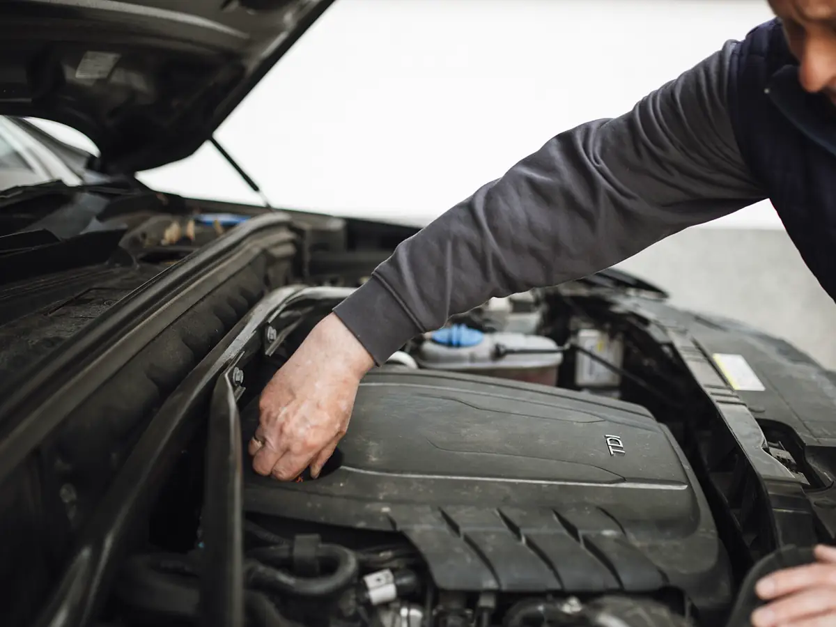 Technician's diagnostic scan tool connected to a vehicle engine bay during a check