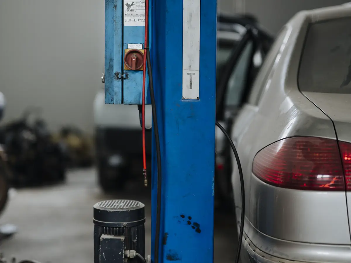 Car raised on a blue two-post lift inside a clean repair shop